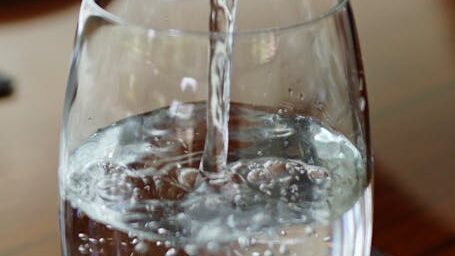 person pouring water on glass